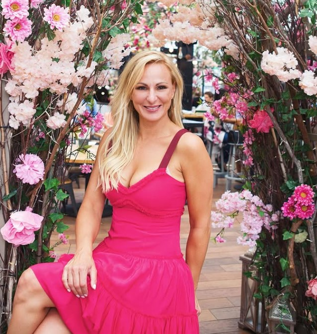 Christi Lukasiak smiling at a Dance Moms cast event, wearing a blazer, blonde hair styled down